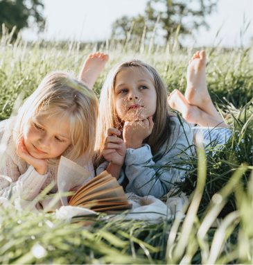 Dos niñas leyendo tumbadas sobre la hierba
