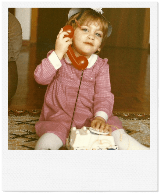 Foto de Cristina, creadora de Kirema Jewels, de pequeña hablando por un teléfono fijo.